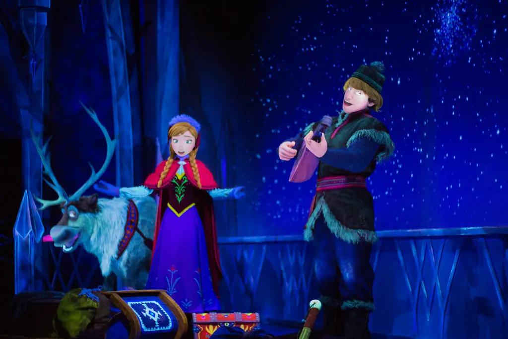 Life-sized audio-animatronic figures of Anna, Kristoff playing a lute, and Sven the reindeer inside the Frozen Ever After attraction, featured in a Hong Kong Disneyland Guide.
