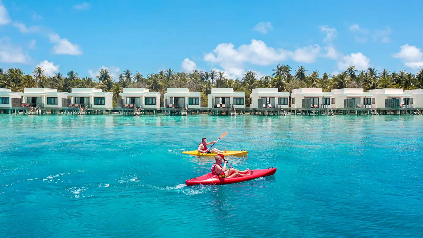 Kayakers Paddling Past Luxury Overwater Bungalows in the Maldives Lagoon